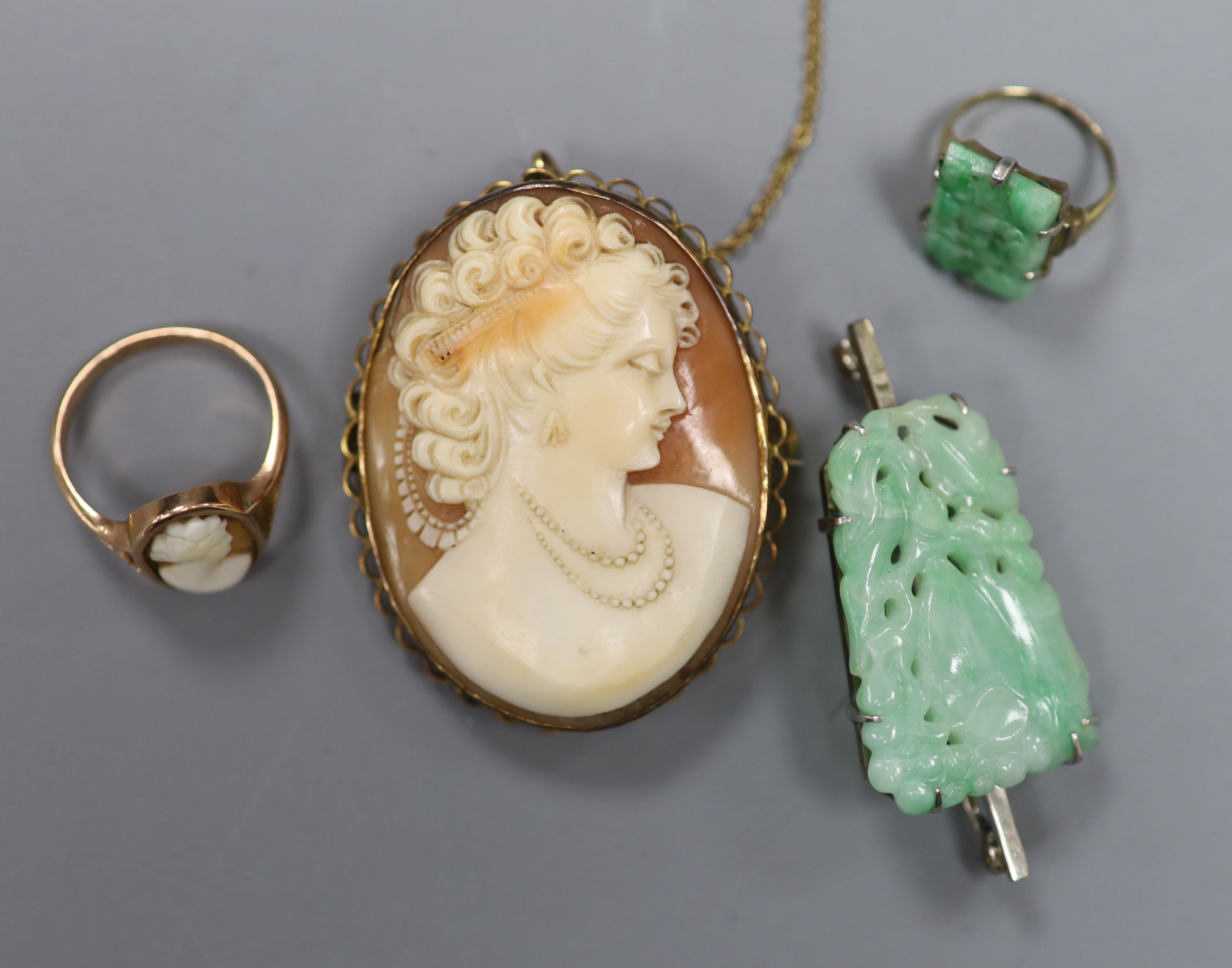A 9ct mounted oval cameo shell brooch, 47mm, gross12.6 grams, two rings including 9ct cameo and yellow metal and jade and a brooch.